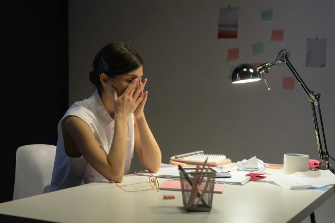 Woman sitting at a desk with her hands on her face, looking tired